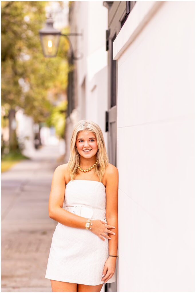 Elegant Charleston senior portraits with a joyful high school senior in a white dress and warm morning light on Meeting Street.