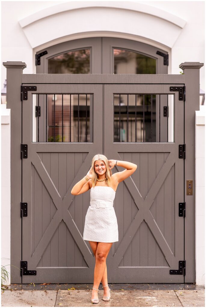 Philip Simmons senior girl laughing in a white dress during her Charleston SC senior portrait session on Meeting Street.