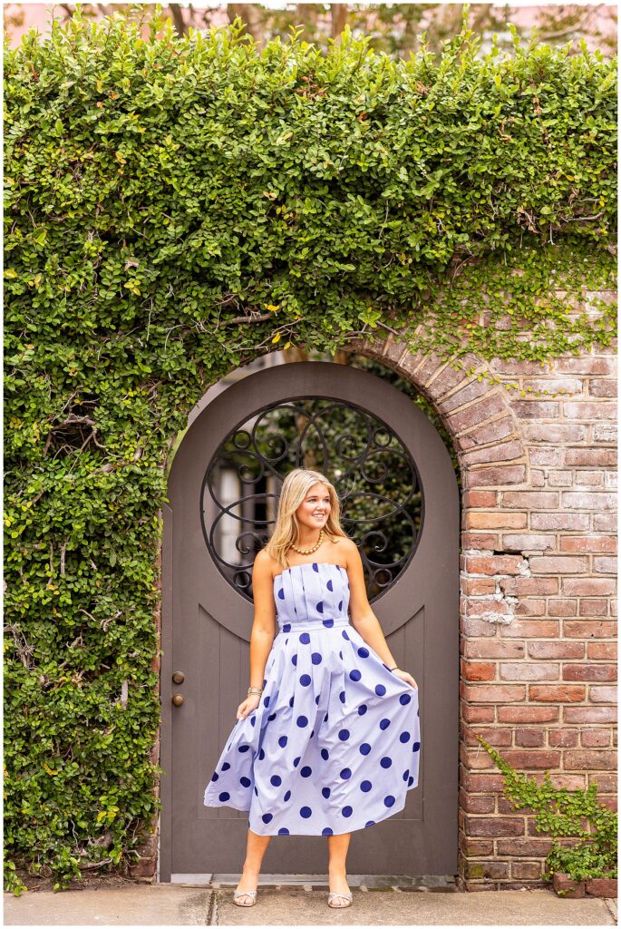 Philip Simmons senior girl in a blue polka-dot dress twirling on Tradd Street during her Downtown Charleston senior session.