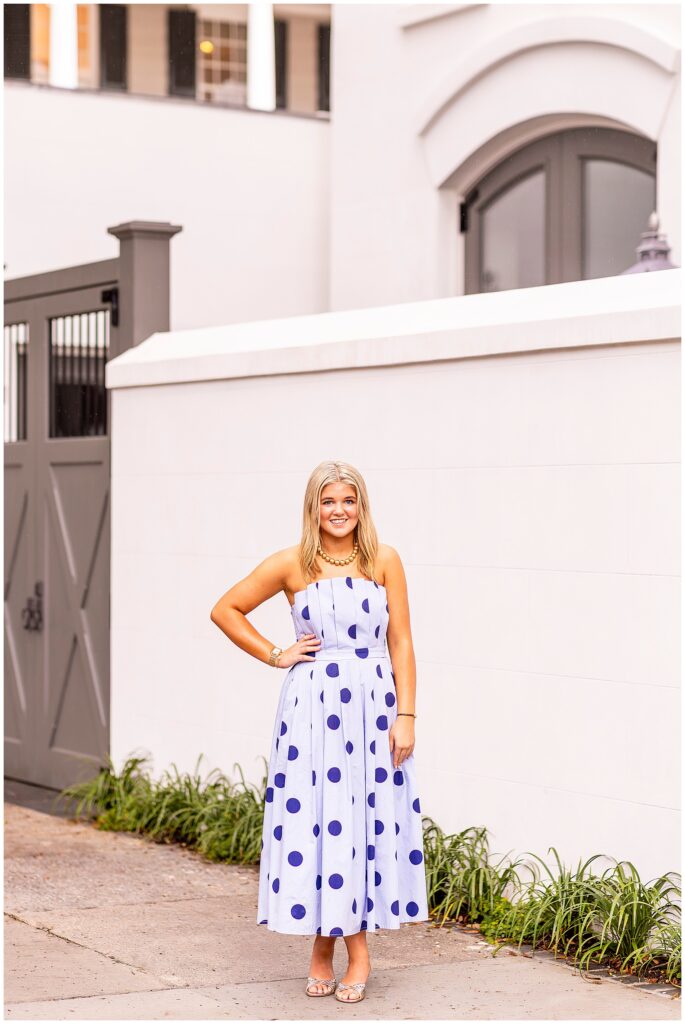 Joyful senior portraits in Downtown Charleston featuring a high school senior in a blue polka-dot dress surrounded by historic architecture.