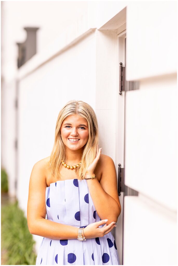 Joyful senior portraits in Charleston featuring a high school senior in a blue polka-dot dress surrounded by historic architecture.