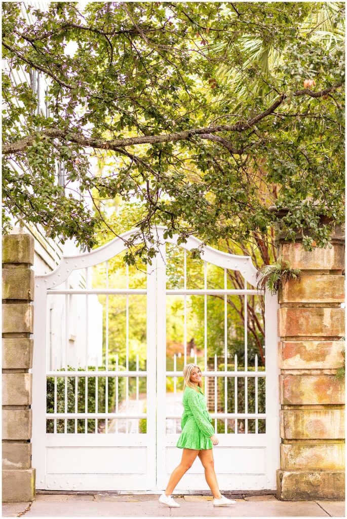 Senior in green dress walking down Meeting Street during her Charleston sunrise senior photography session.