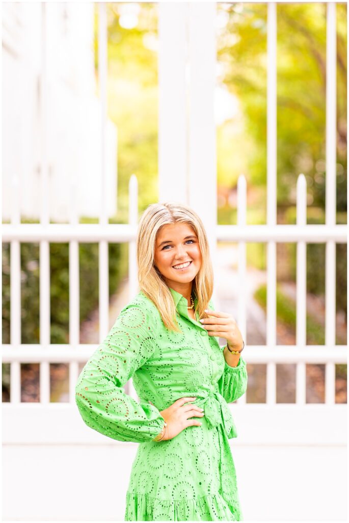 Chic senior portraits in Charleston SC featuring a senior girl in a green dress surrounded by colorful homes and glowy light.