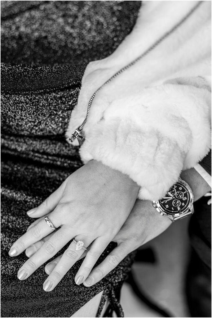 Close-up of intertwined hands showcasing Taylor’s engagement ring.