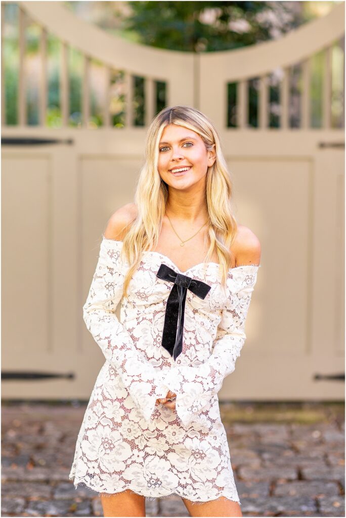 Bella laughing with the wind in her hair on a historic street near Rainbow Row during her senior session.
