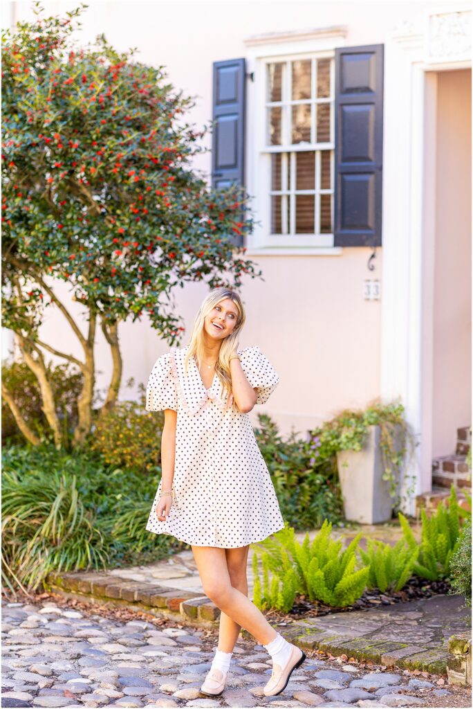 Bella twirling on steps of a Charleston home on Tradd Street, smiling at the camera for senior portraits.