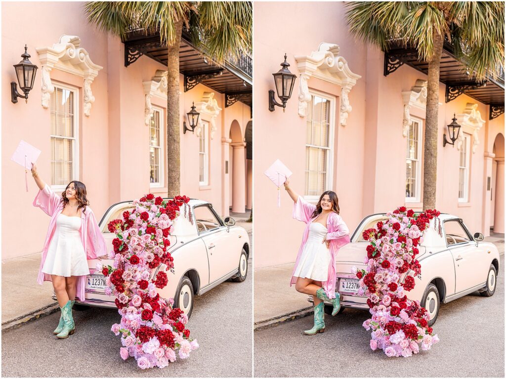 A Charleston senior in a pink graduation gown, holding her pink cap in the air, as she poses next to a pink car called The Pink Figgy that is dressed in red and pink floral garland