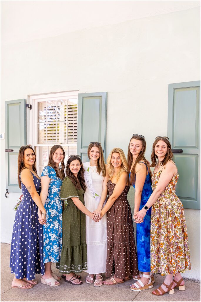Bride and bridesmaids posing in front of pastel homes on Rainbow Row during a Charleston bachelorette photoshoot