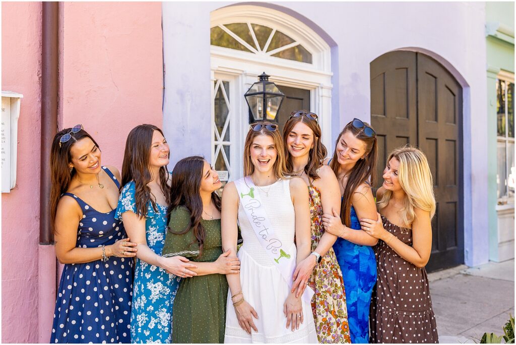 Group of bridesmaids laughing together on Rainbow Row in Charleston during bachelorette photoshoot