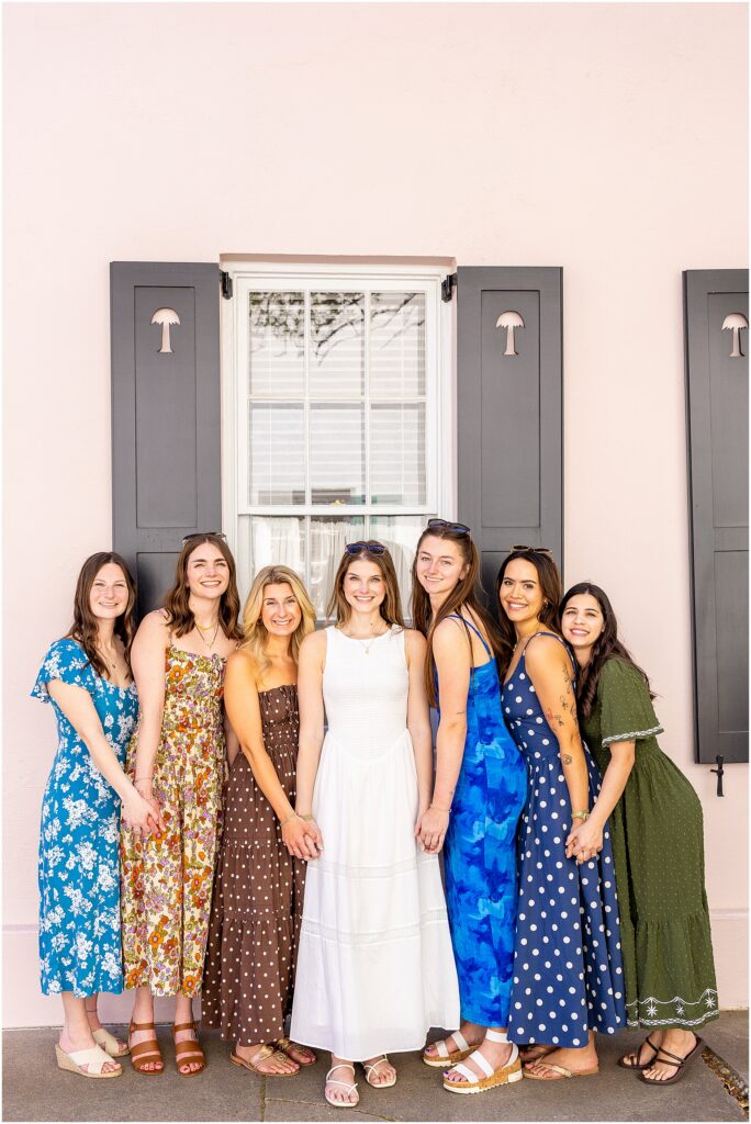 Bride and bridesmaids posing in soft evening light on Rainbow Row in Charleston