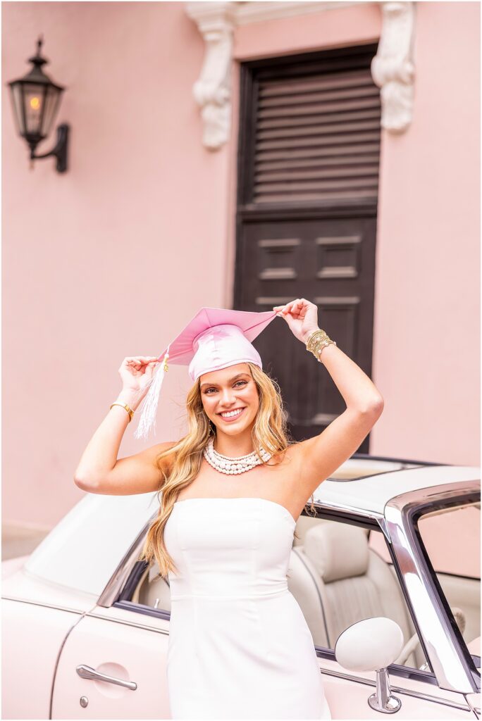 Fun senior photo of a high school girl wearing a pink cap and leaning against The Pink Figgy in Charleston