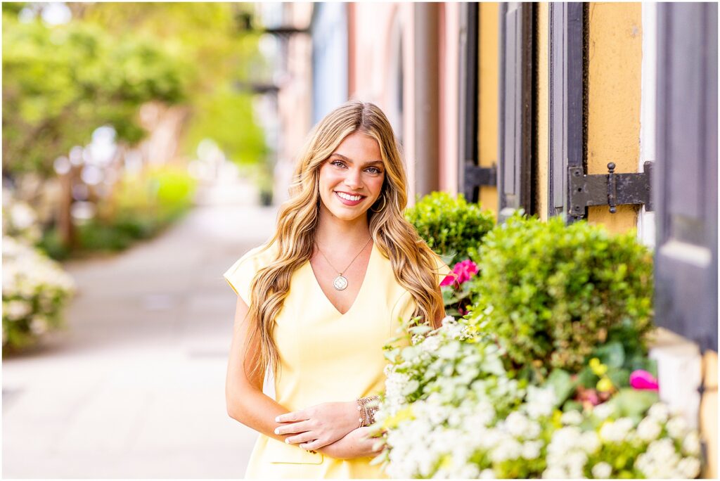 Senior portrait at Rainbow Row Charleston with pastel historic homes and window boxes