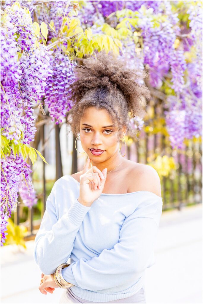 Senior girl posing under blooming wisteria in Charleston SC during a spring photoshoot