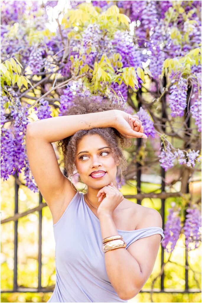 High school senior posing in front of wisteria in Charleston SC during spring season