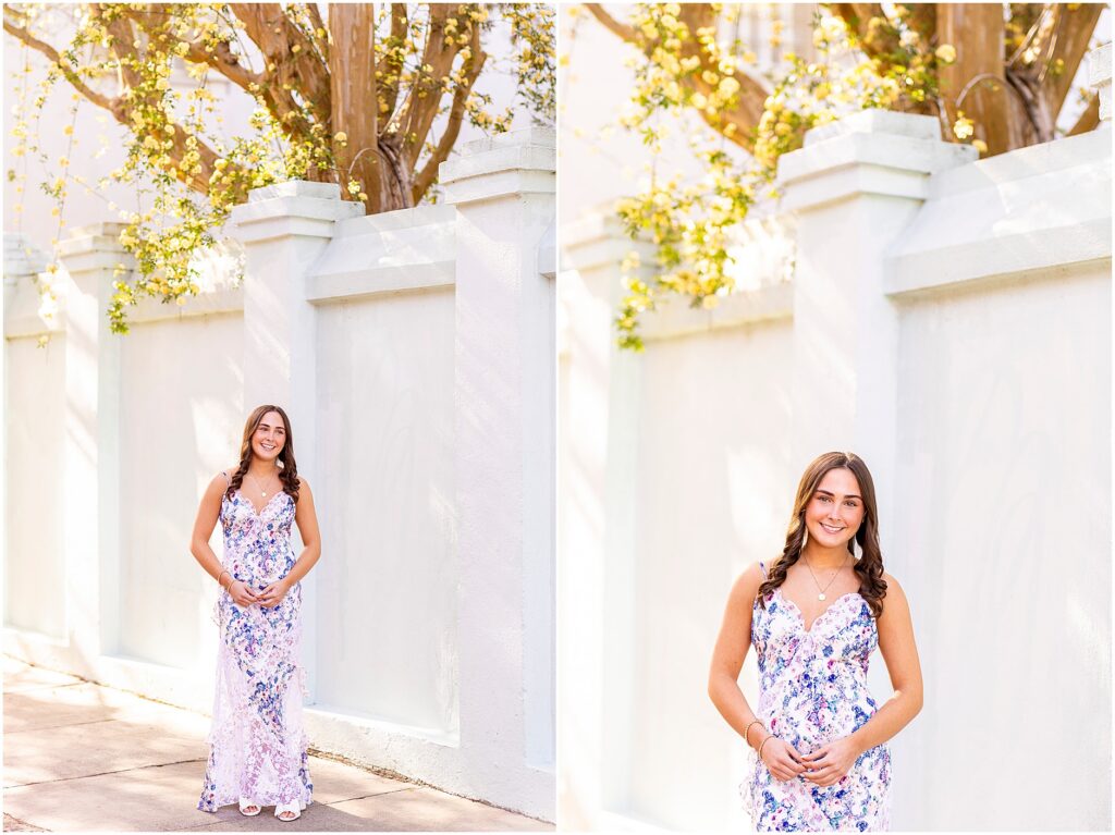Charleston senior photos of a girl in a floral dress standing by a pastel blue home along Rainbow Row