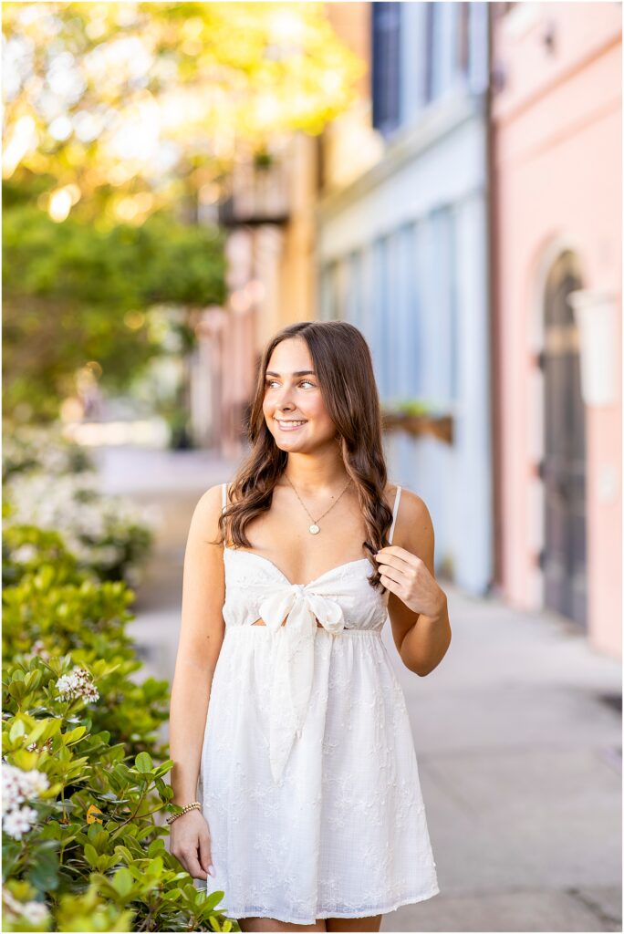 Senior portrait on Rainbow Row in Charleston with pastel homes as the backdrop