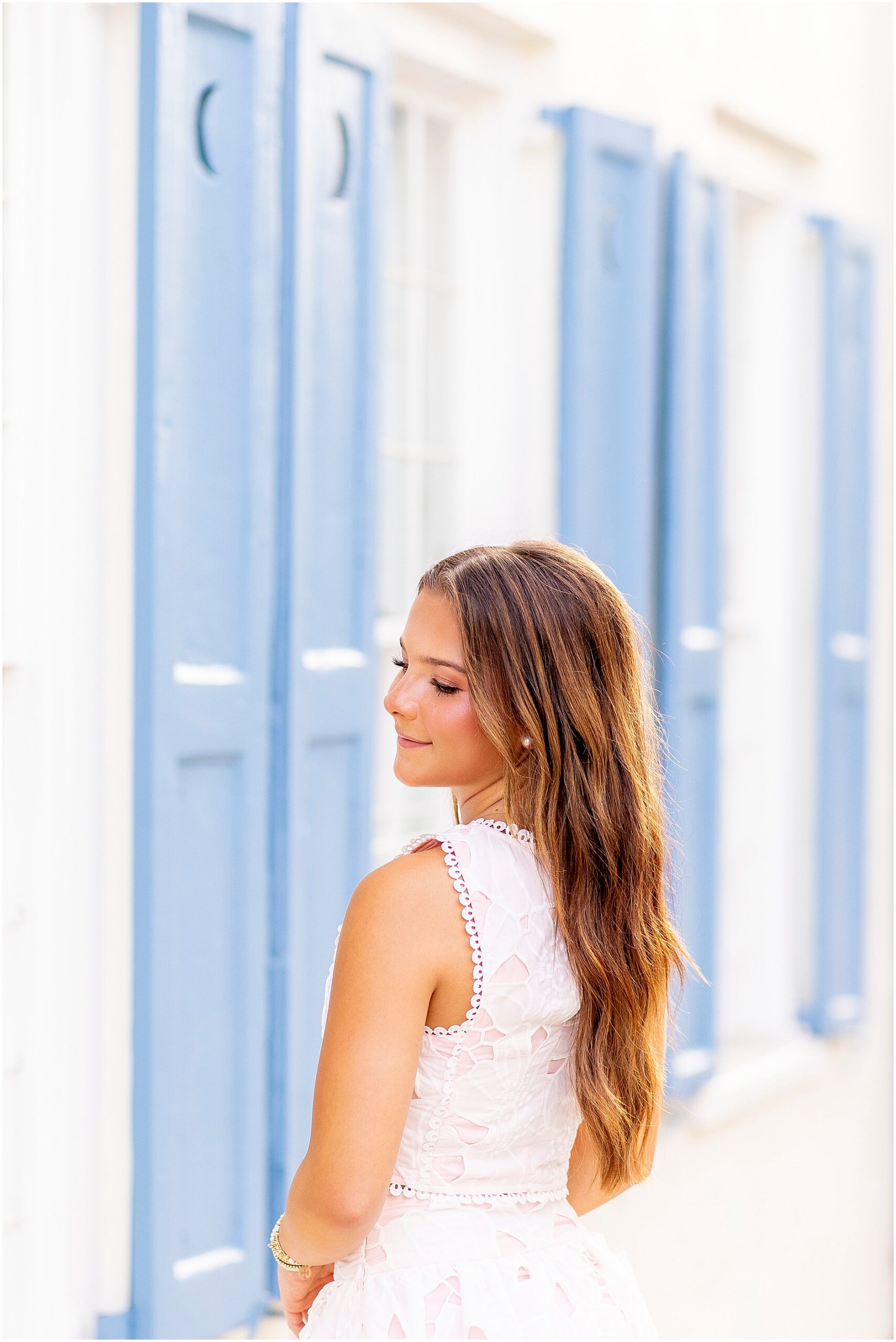 Angelic senior photo of a girl smiling softly over her shoulder as she poses on Tradd Street in Charleston, South Carolina