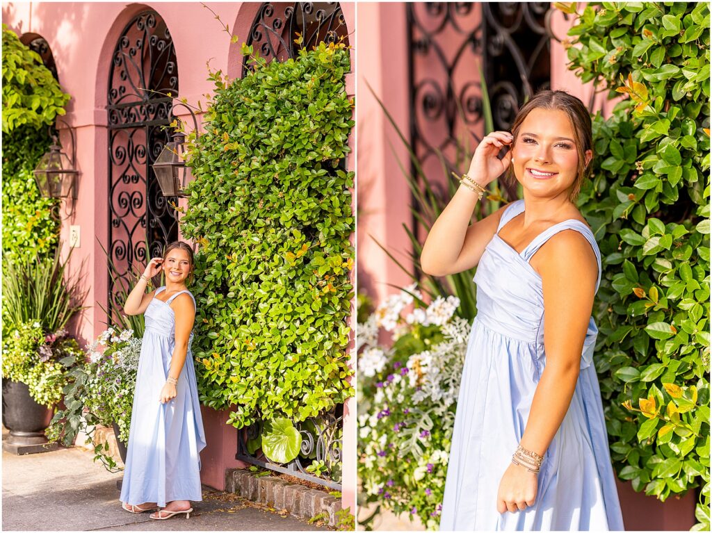 Charleston senior in baby blue dress with a big bow on the back posing with a pink home and greenery on Rainbow Row