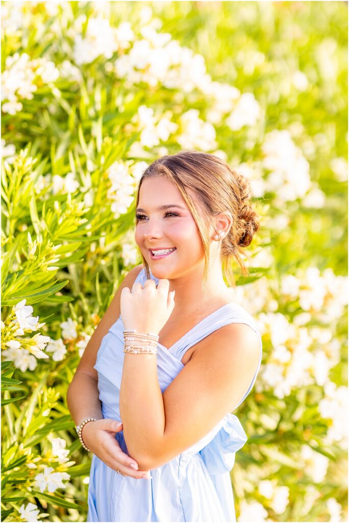 High school senior girl posing with white florals behind her on The Battery in Charleston