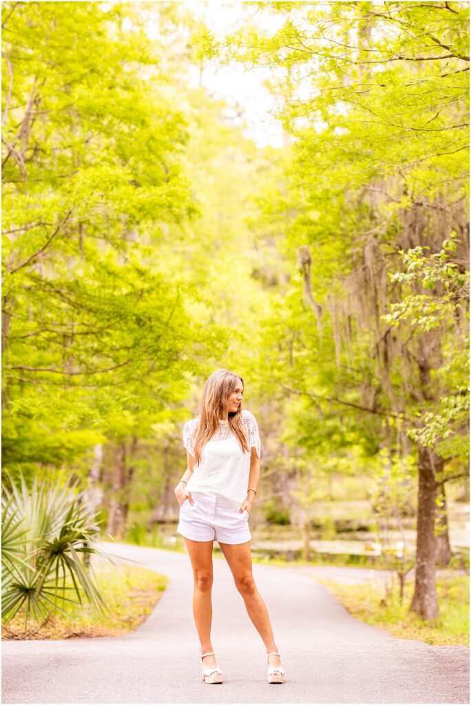Charleston Southern graduate posing in Cypress Gardens during a Charleston senior photo session surrounded by greenery and Spanish moss.