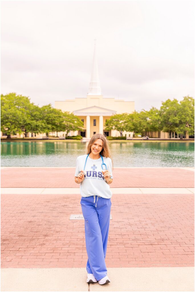 College nursing graduate smiling beside the reflection pond at Charleston Southern University.