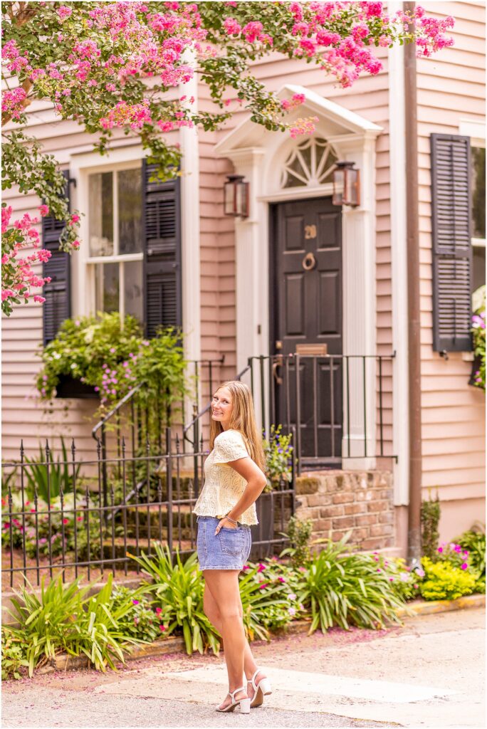 Senior celebrating graduation with colorful Rainbow Row homes creating a classic Charleston backdrop