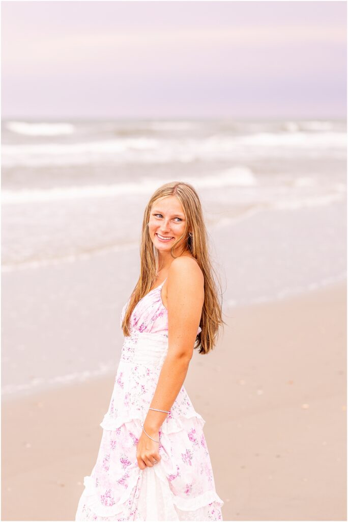 High school senior walking along the shoreline at Isle of Palms during a golden hour beach senior session