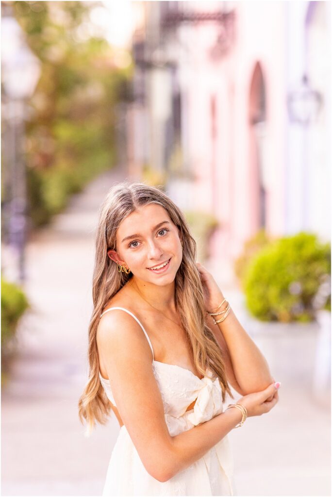 High school senior smiling along Rainbow Row during a destination senior photography session in Charleston, South Carolina.
