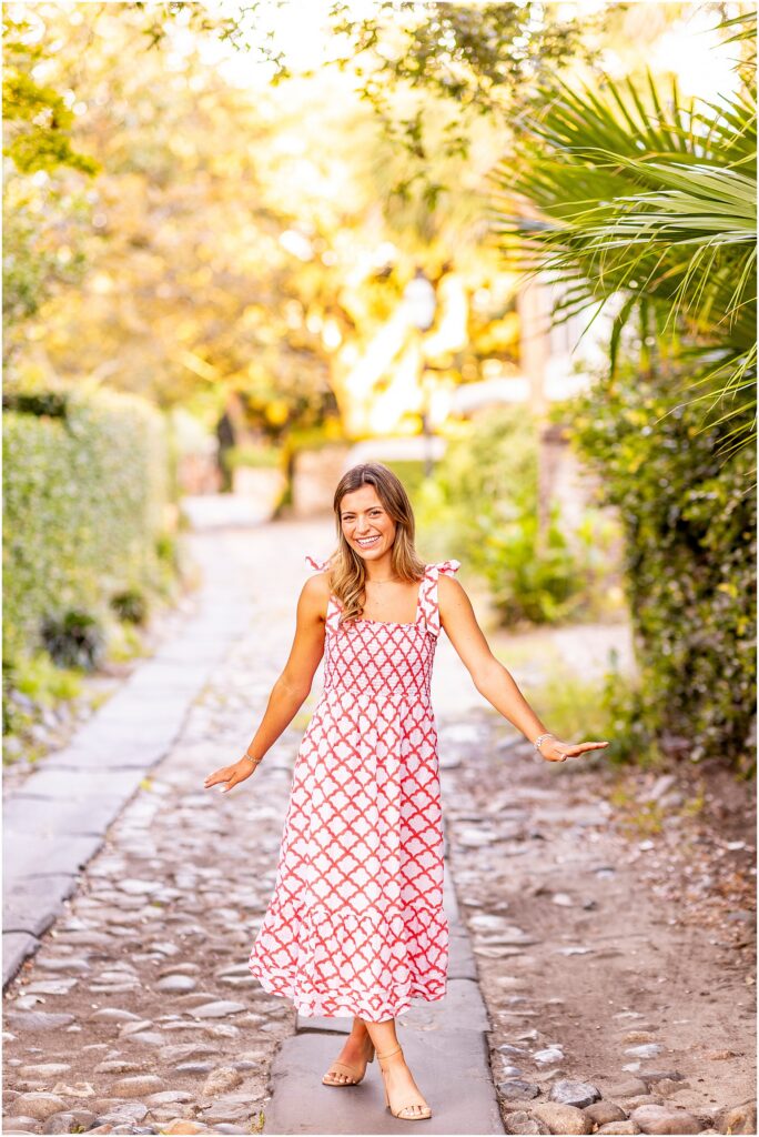 Charleston senior photography featuring a senior girl in a white and red dress among the colorful historic streets of Rainbow Row