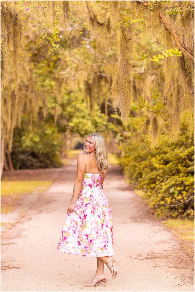 Vibrant Hampton Park senior portrait of a girl in a colorful pink dress surrounded by lush Lowcountry greenery and Spanish moss