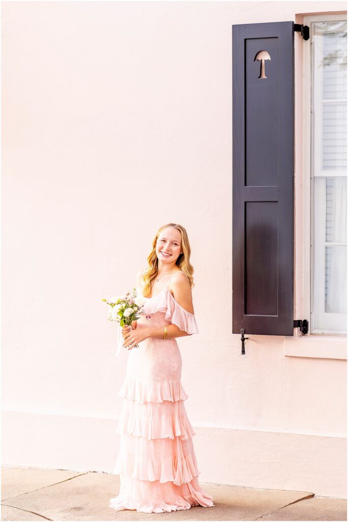 Charleston senior portrait of Ellie in a pink dress along the colorful historic homes of Rainbow Row in Charleston, South Carolina