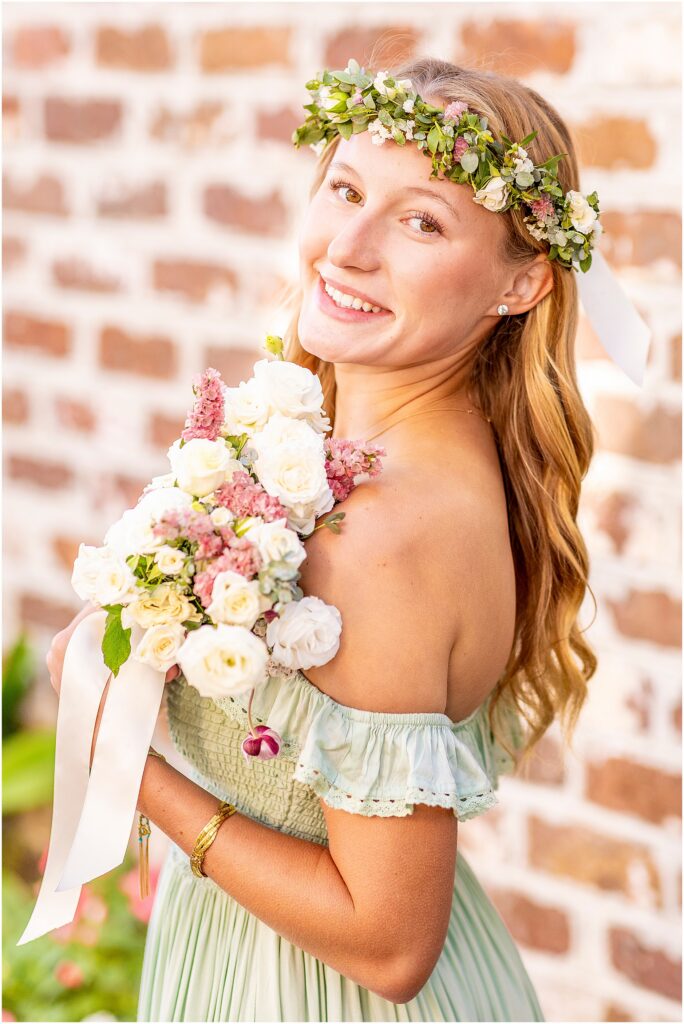 Charleston SC senior portrait featuring Ellie in a green dress and flower crown with historic South of Broad homes